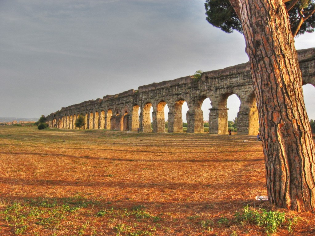 Picture of an ancient Roman aqueduct with dry ground surrounding it.